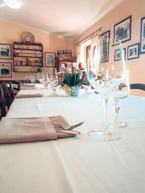 Une salle à manger avec une longue table dressée pour un repas, agrémentée de beaux verres transparents et de serviettes pliées.