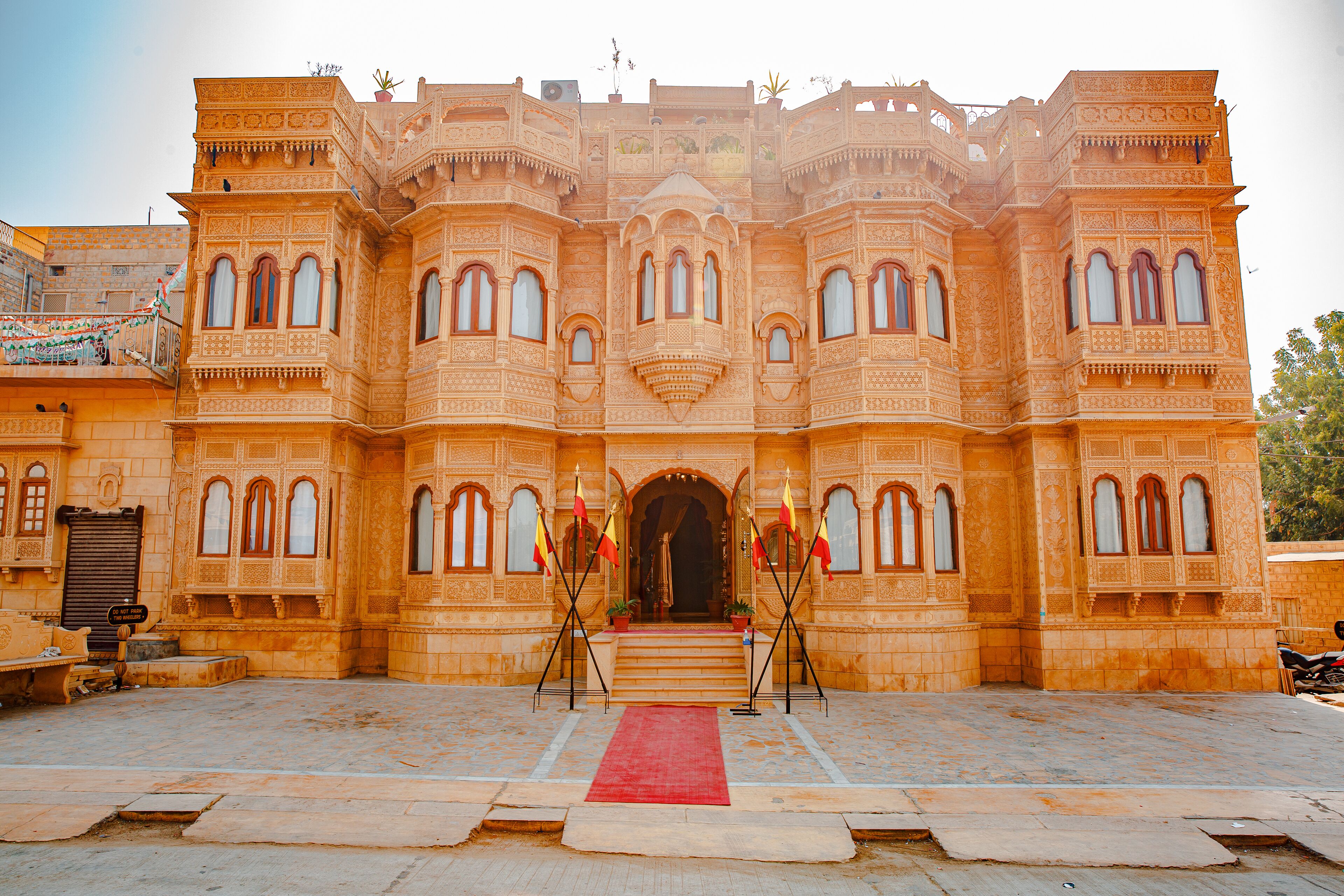 A grand building with intricate architecture, a red carpet, and flags at the entrance.