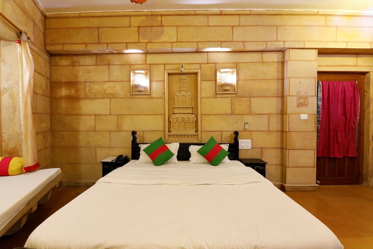 Ein Hotelzimmer mit einem großen Bett, zwei Nachttischen, einer Wandlampe und einer Tür mit rotem Vorhang.