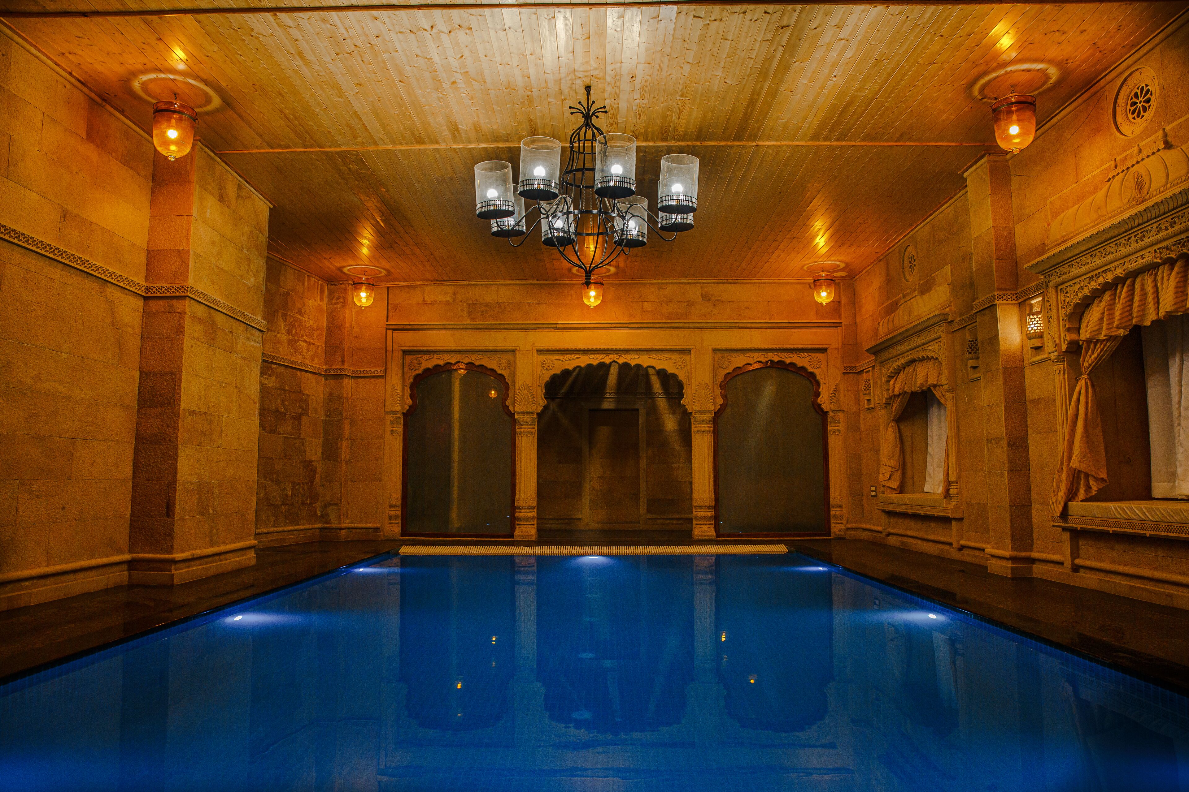 Una amplia piscina cubierta con techo de madera y columnas ornamentadas.