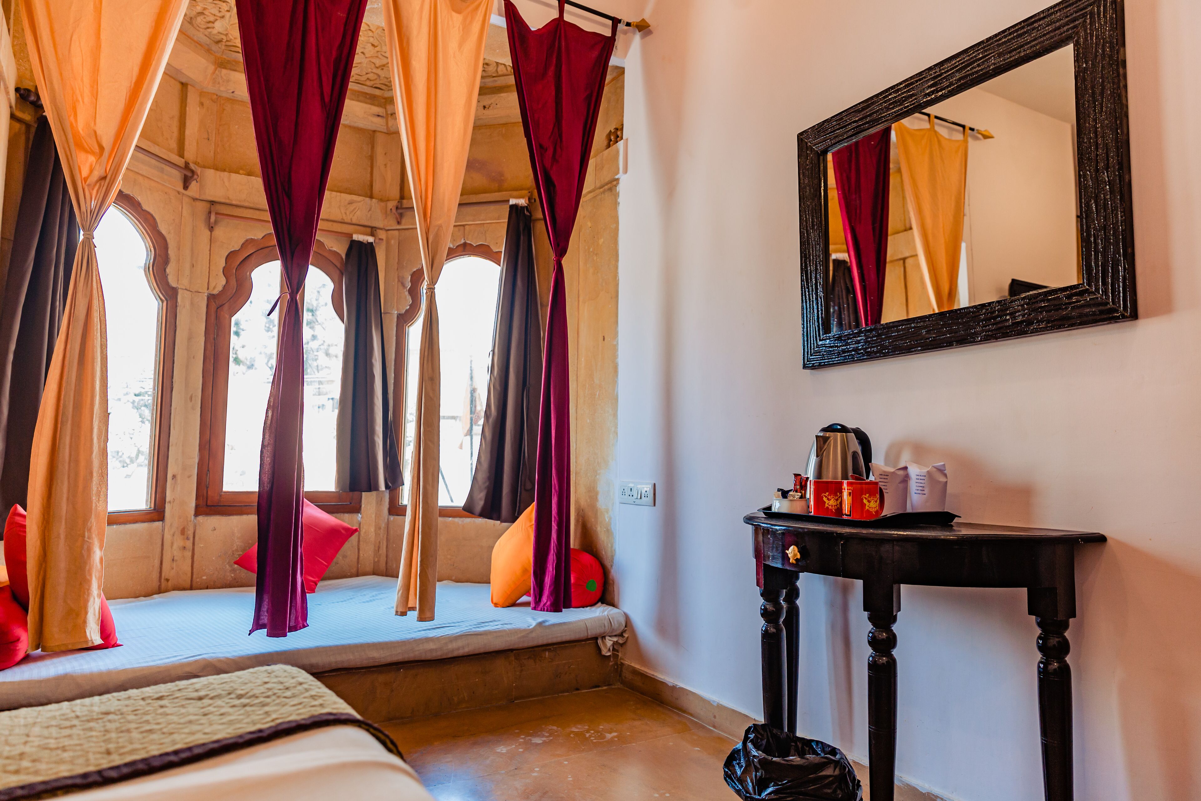 A room with a bed, a table, a mirror, and curtains.