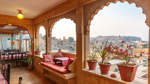 Une pièce de style traditionnel, avec un banc en bois, un coin repas et une vue sur le paysage urbain à travers des fenêtres en arc de cercle.