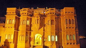 Un grand bâtiment imposant, richement décoré, avec de nombreuses arcades et des sculptures en pierre détaillées, illuminé la nuit.