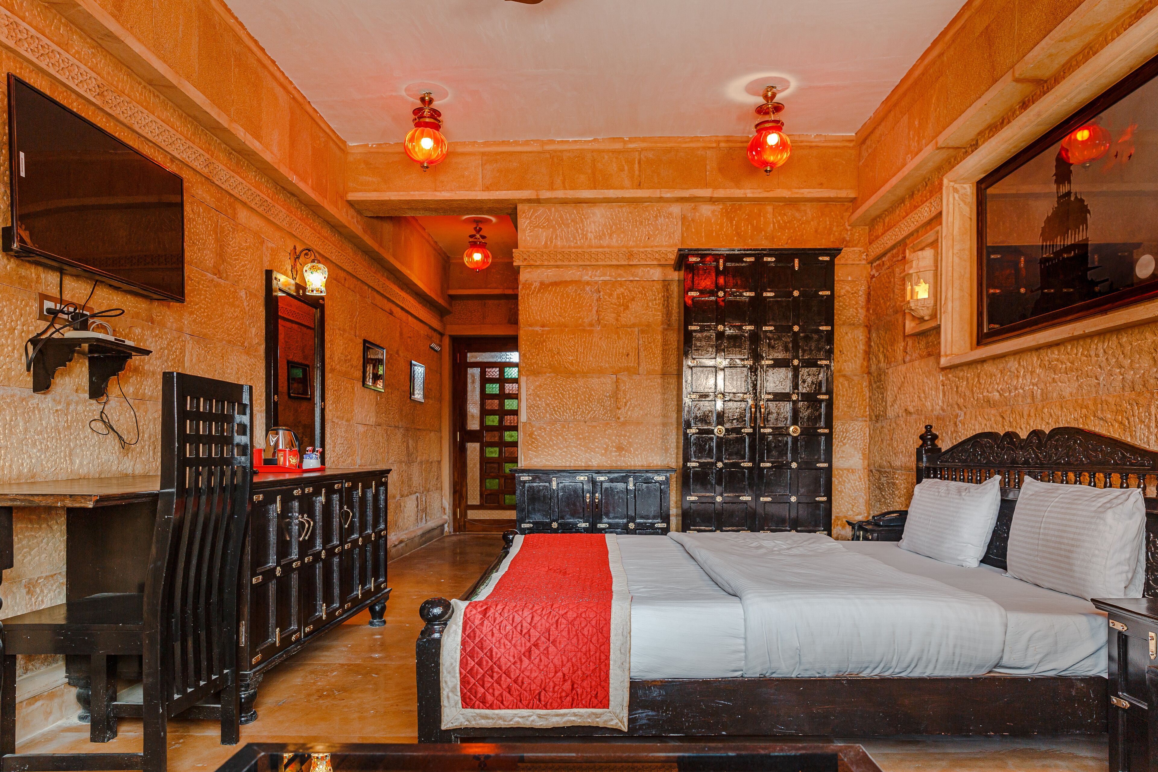 A spacious hotel room with a large bed, a desk, and a wardrobe.