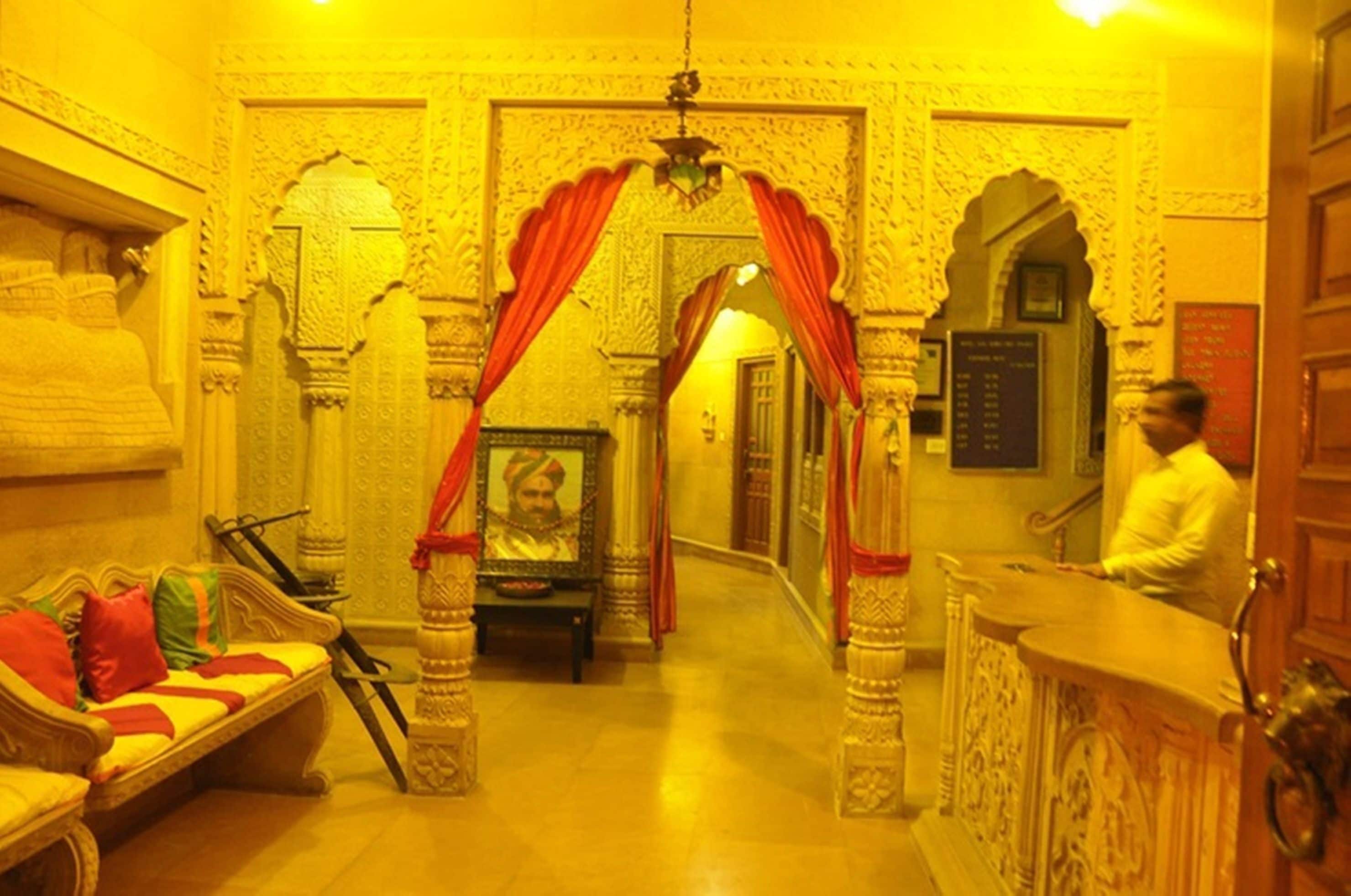 An ornate room with a sofa, a framed portrait, and a reception desk.
