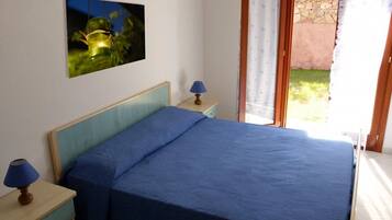 Quarto com cama, duas mesas de cabeceira com luminárias, um quadro na parede e vista para o exterior.