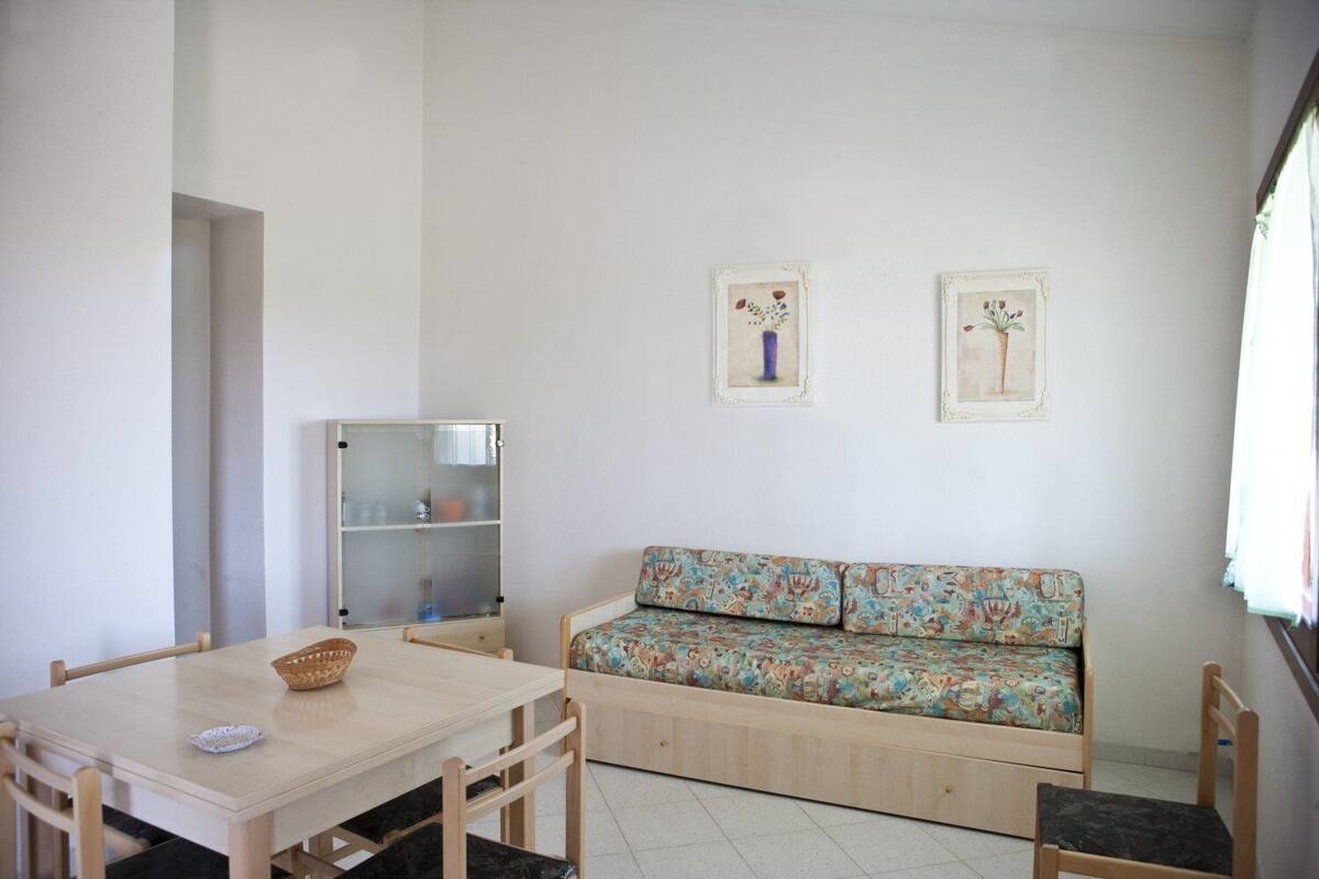 A room with a wooden table, a sofa, a cabinet, and two wall-mounted pictures.