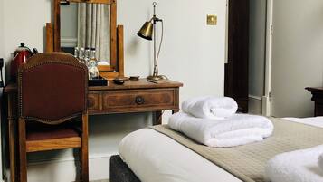 A hotel room with a bed, a desk, a chair, a lamp, and a mirror.