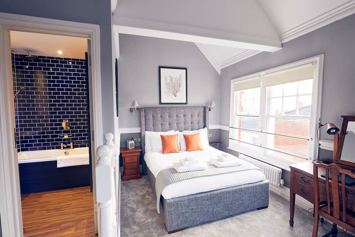Quarto com cama grande, mesa de cabeceira, cômoda e janela com vista.