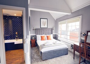 A bedroom with a large bed, a nightstand, a dresser, and a window with a view. - The Old Coffee Tavern (Warwick)