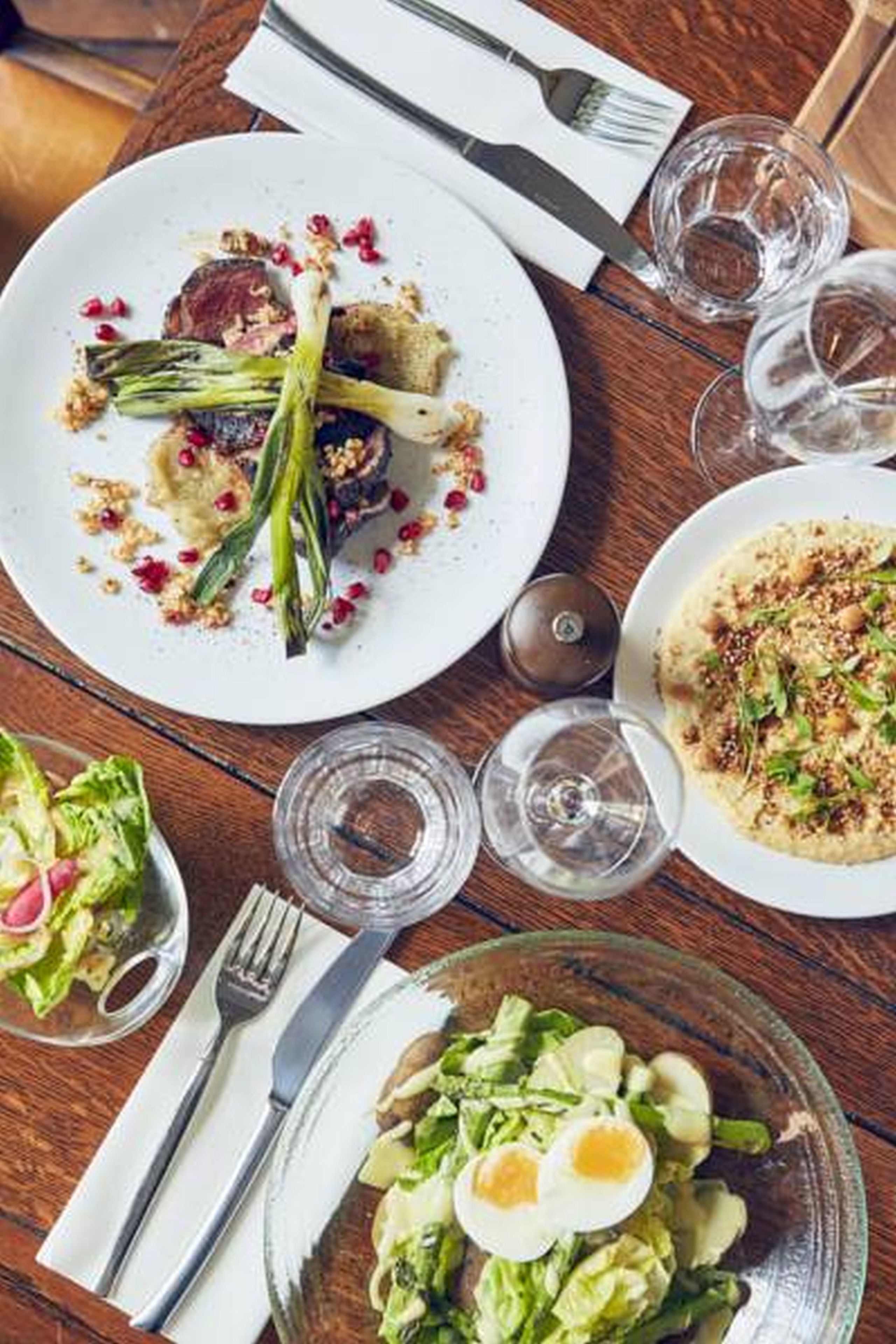A dining table with plates of food, glasses of water, and cutlery.