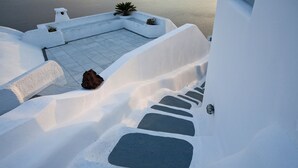 A white-walled building with a stone pathway leading to a terrace. - Aspa Caves (Santorini)