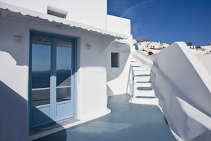 Un edificio blanco con una puerta azul y una escalera que sube a un nivel superior.