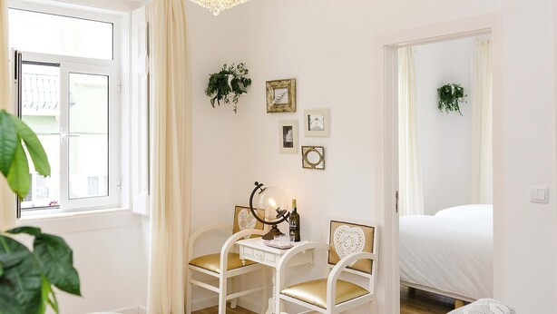A bedroom with a bed, a desk with a lamp, two chairs, and a chandelier. - LisbonBCStays by LCH (Lisbon)