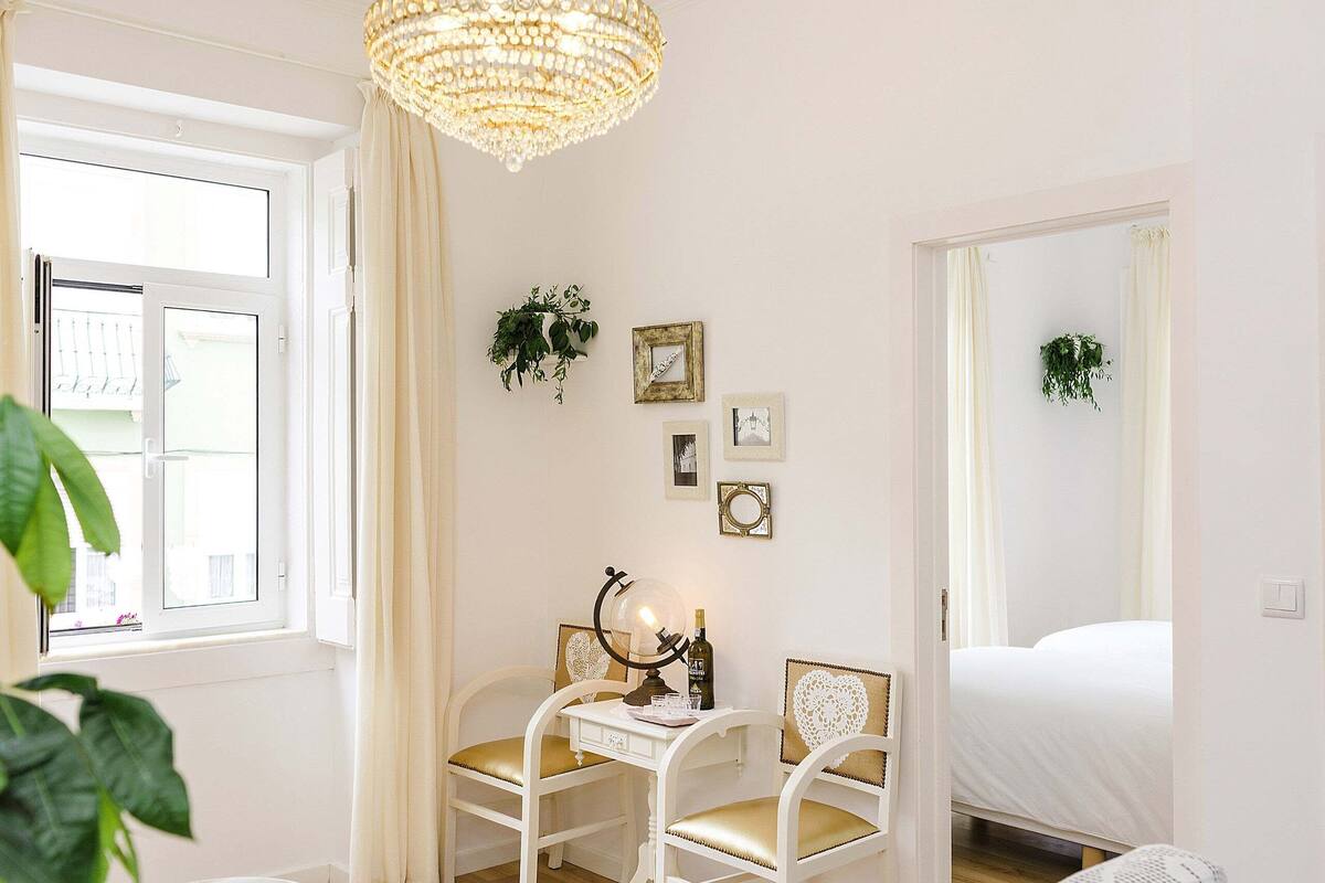 Ein Schlafzimmer mit einem Bett, einem Schreibtisch mit Lampe, zwei Stühlen und einer Chandelier.