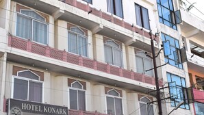 Un hotel de varios pisos con balcones y un letrero que indica que es el Hotel Konark Palace.