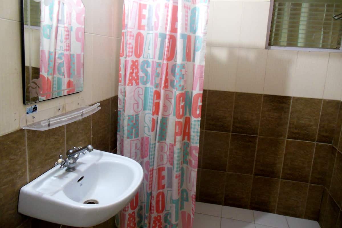 Un baño con lavamanos blanco, un espejo y una cortina de ducha con texto.