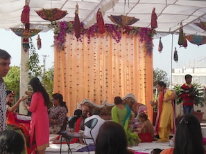 Un espacio decorado para un evento, con un escenario, asientos para el público y adornos colgantes.