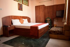 Un dormitorio con una cama de madera, una mesita de noche, un televisor y una silla verde.