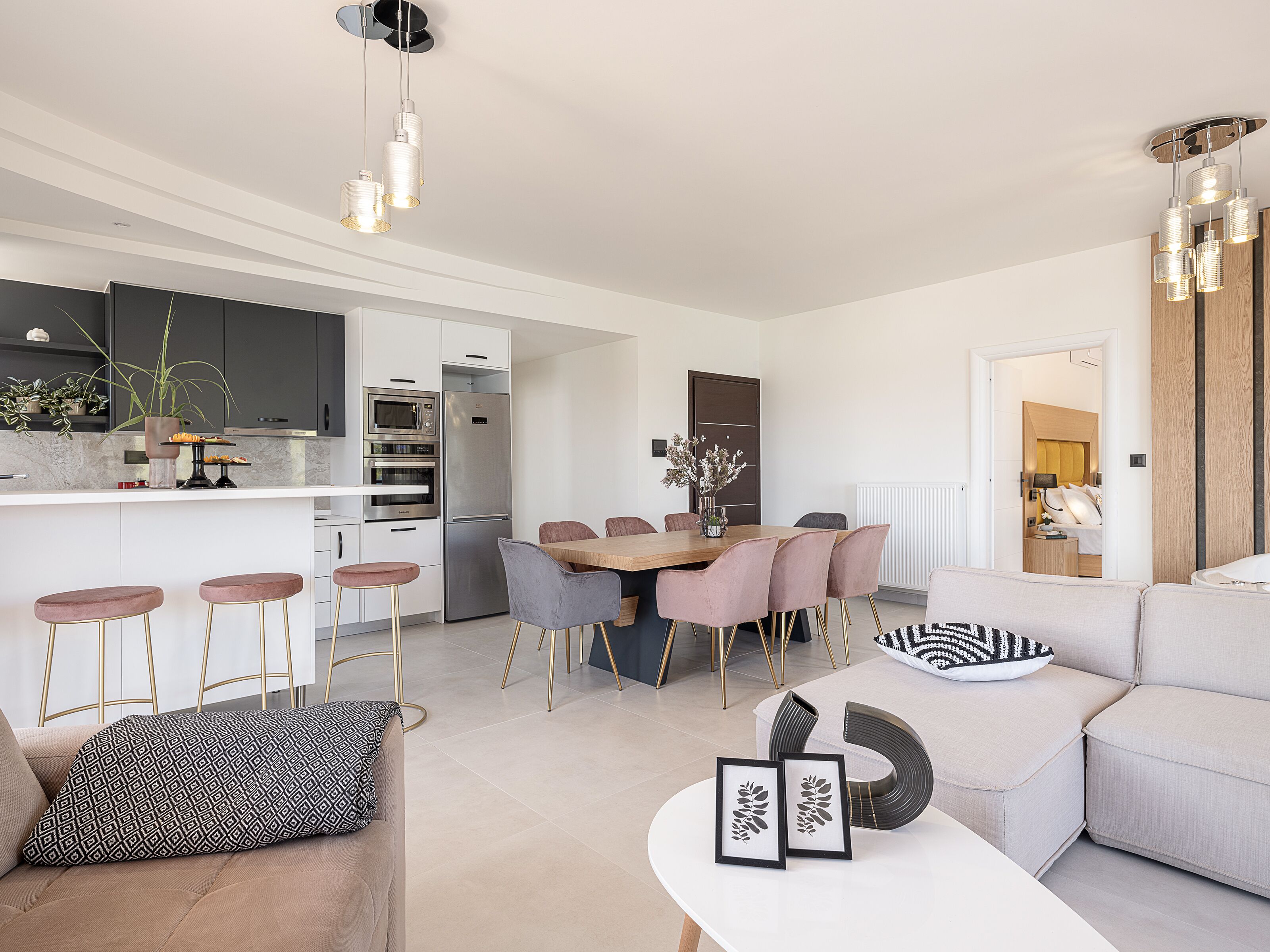 Een moderne keuken met roestvrijstalen apparatuur, een eethoek met een houten tafel en stoelen, en een zithoek met een bank en salontafel.