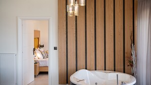 A modern bathroom with a freestanding bathtub, wooden panel wall, and a hanging light fixture. - Elia Seaside Nea Chora (Chania)