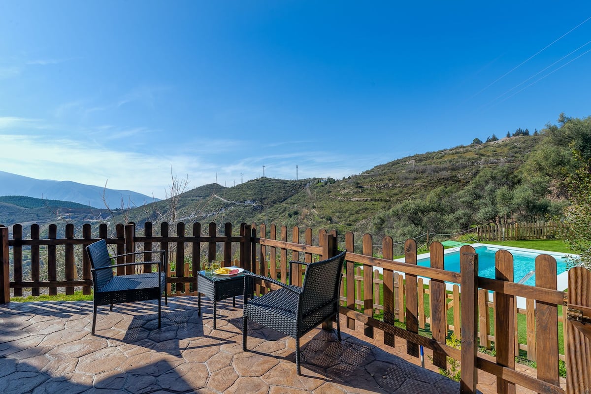 Une terrasse avec deux chaises et une table, une clôture en bois et une piscine.