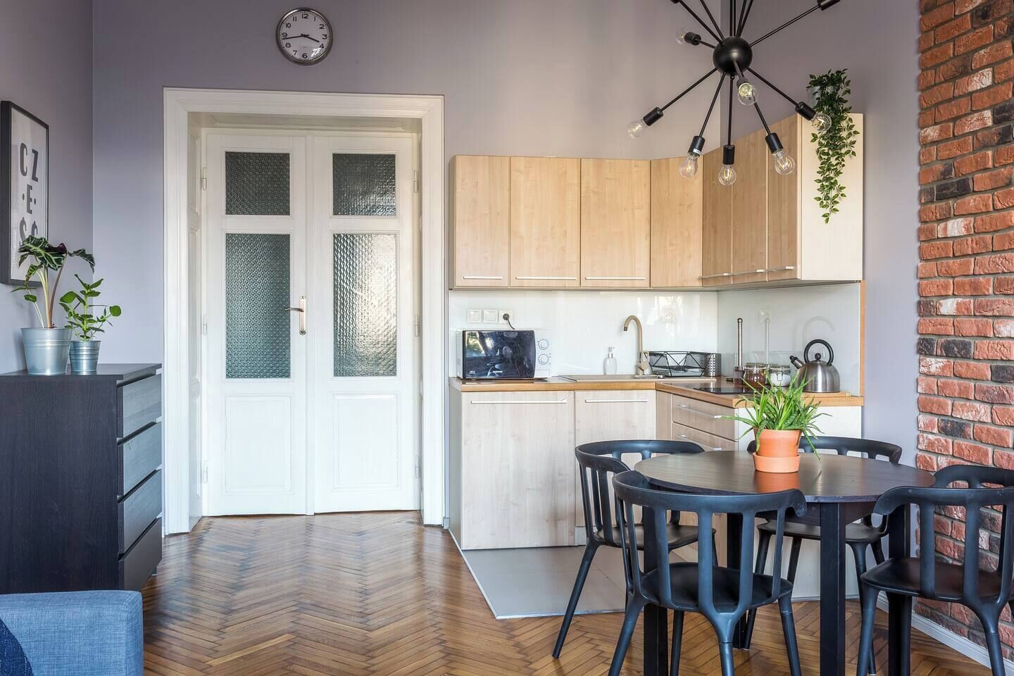 Una cocina moderna con armarios de madera, una mesa de comedor con sillas y un reloj en la pared.