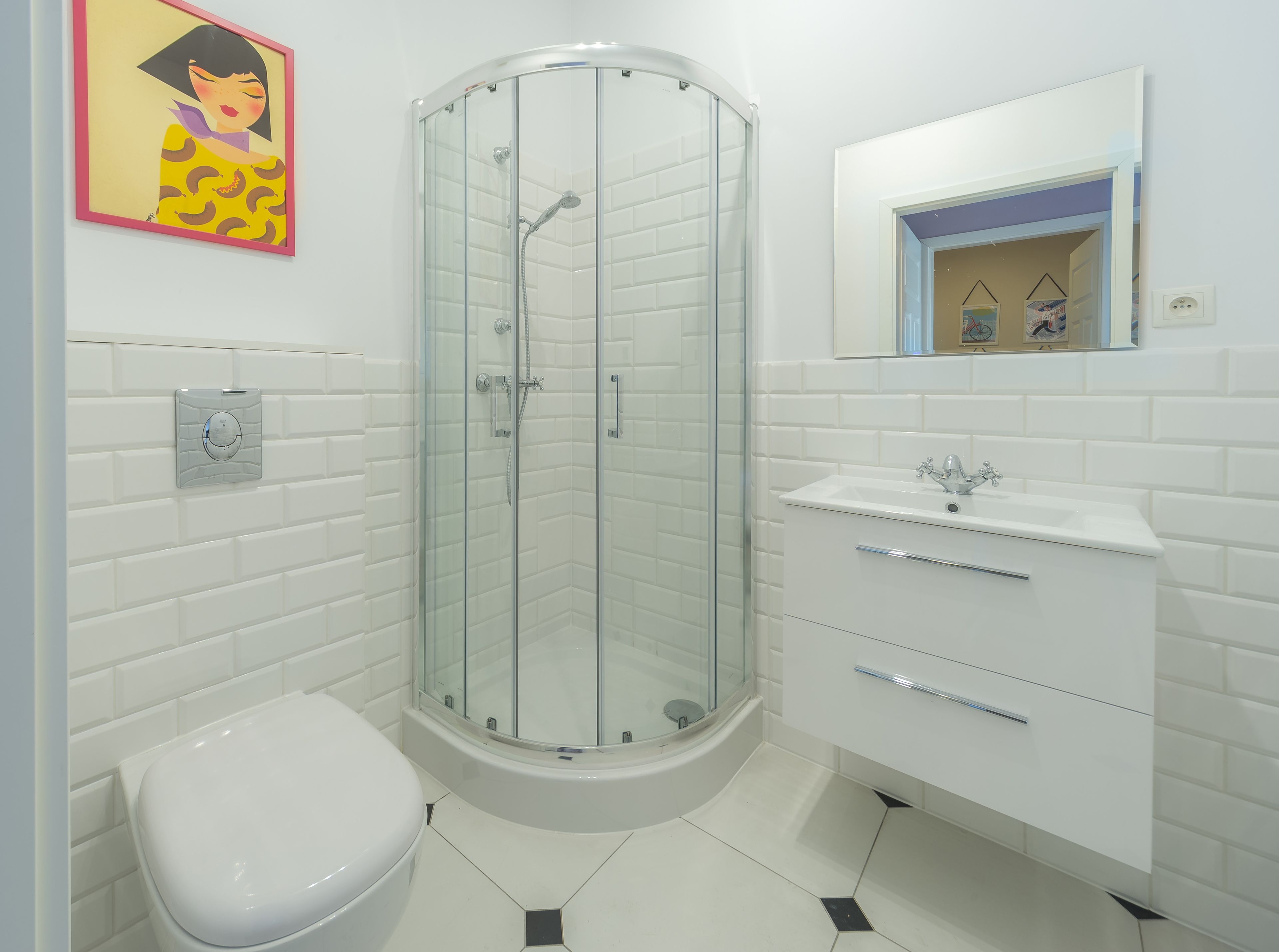 Een moderne badkamer met een douchecabine van glas, een wit toilet en een wastafel met spiegel.