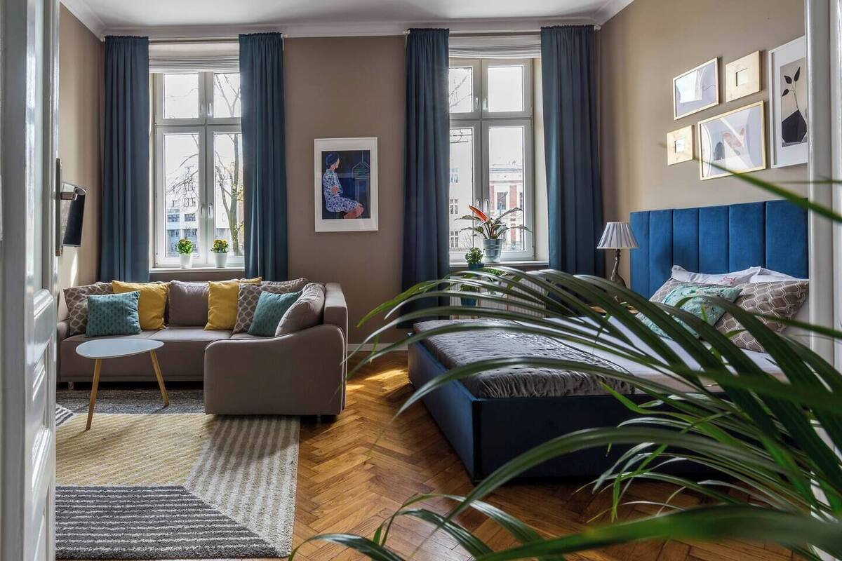 Una sala de estar con un sofá, una mesita, un sofá azul y una planta grande.