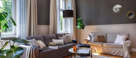 A living room with two sofas, a coffee table, a floor lamp, and a large window.