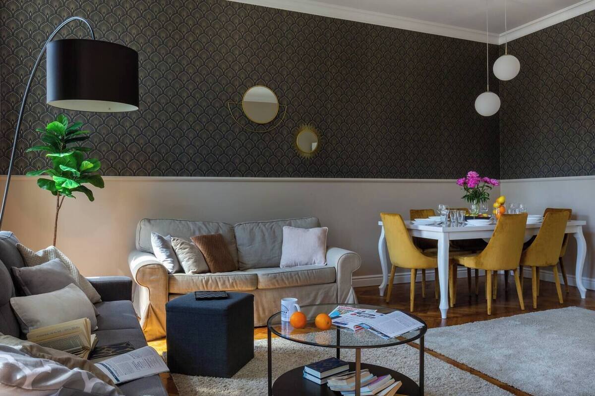 A modern living room with a sofa, coffee table, and dining area with chairs.
