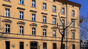 En bygning med flere etager, en symmetrisk facade, jævnt placerede vinduer og en central indgang med en dekorativ bue.
