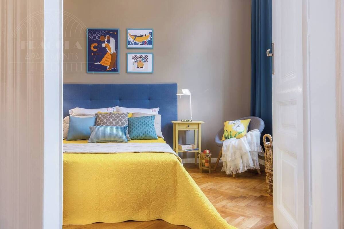 Une chambre à coucher avec un lit, une table de chevet, une chaise et une œuvre d’art accrochée au mur.
