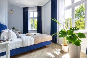 Una camera da letto con un letto, un comodino, una pianta in vaso e una finestra con tende.