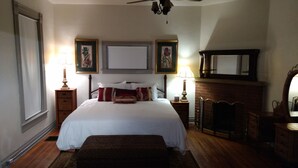 A bedroom with a large bed, two bedside tables with lamps, a fireplace, and framed pictures on the wall. - Beautiful Downtown Indy Guest Homes (Indianapolis)