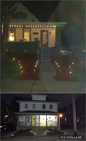A two-story house with a front porch, a visible door, and a small garden area with lights. - Beautiful Downtown Indy Guest Homes (Indianapolis)