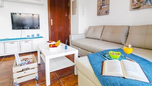 Un salon avec un canapé, une table basse, un téléviseur et une bibliothèque.