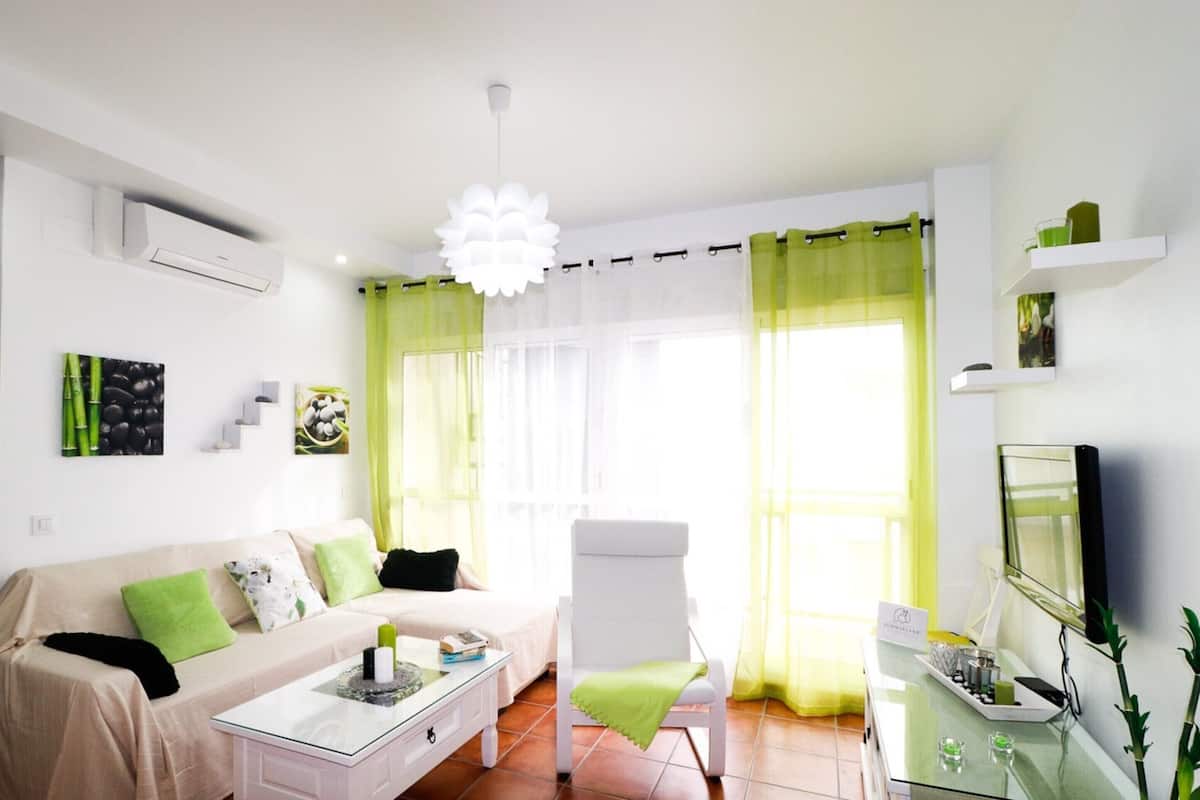 Een moderne woonkamer met een bank, fauteuil, salontafel, televisie en een glazen kast.