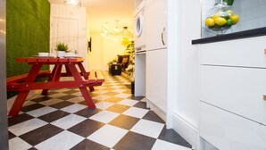 A kitchen with a checkered floor, a red picnic table, and a white refrigerator. - Modern Design House (Liverpool)