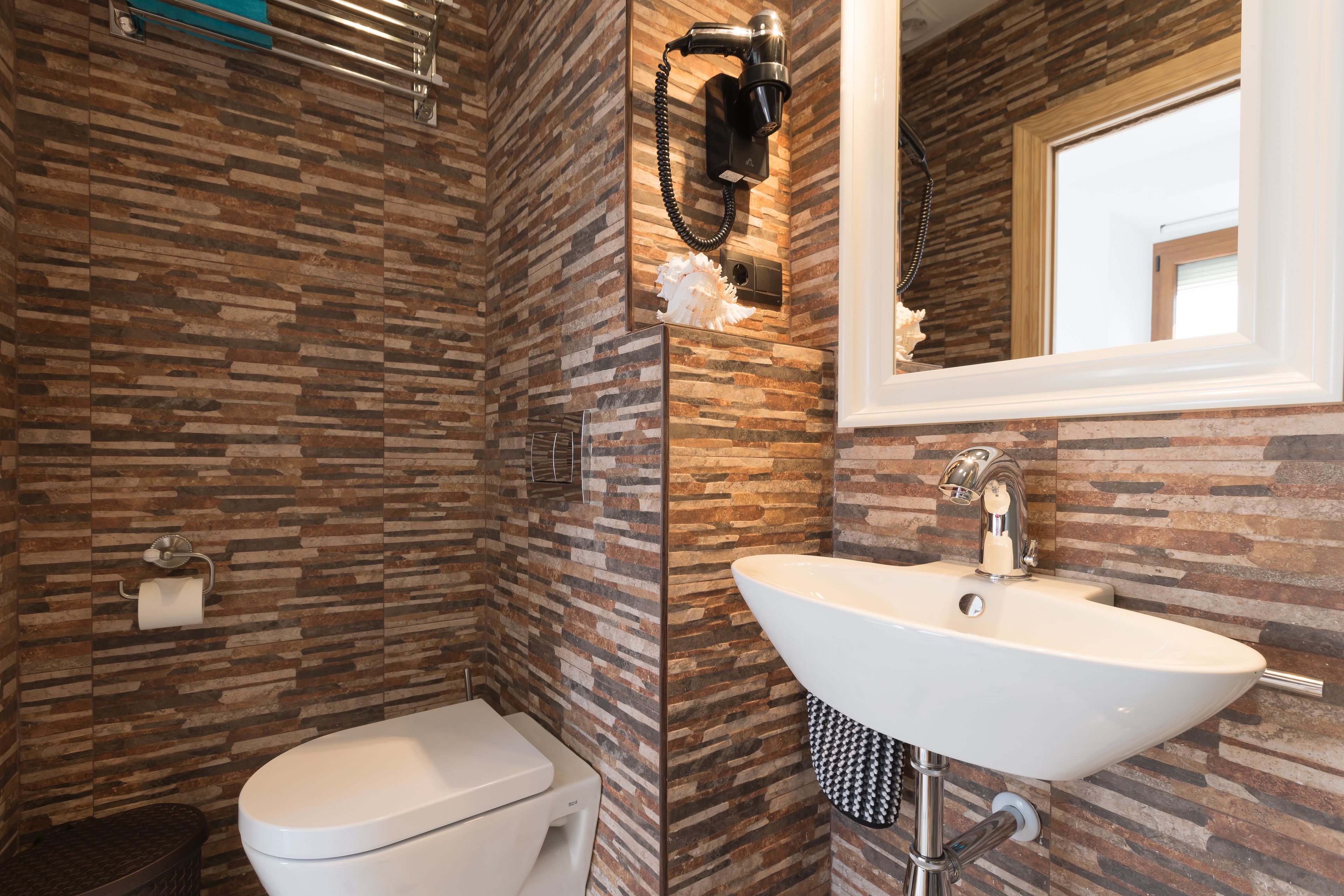 A bathroom with a modern design, featuring a toilet, a sink, and a mirror.