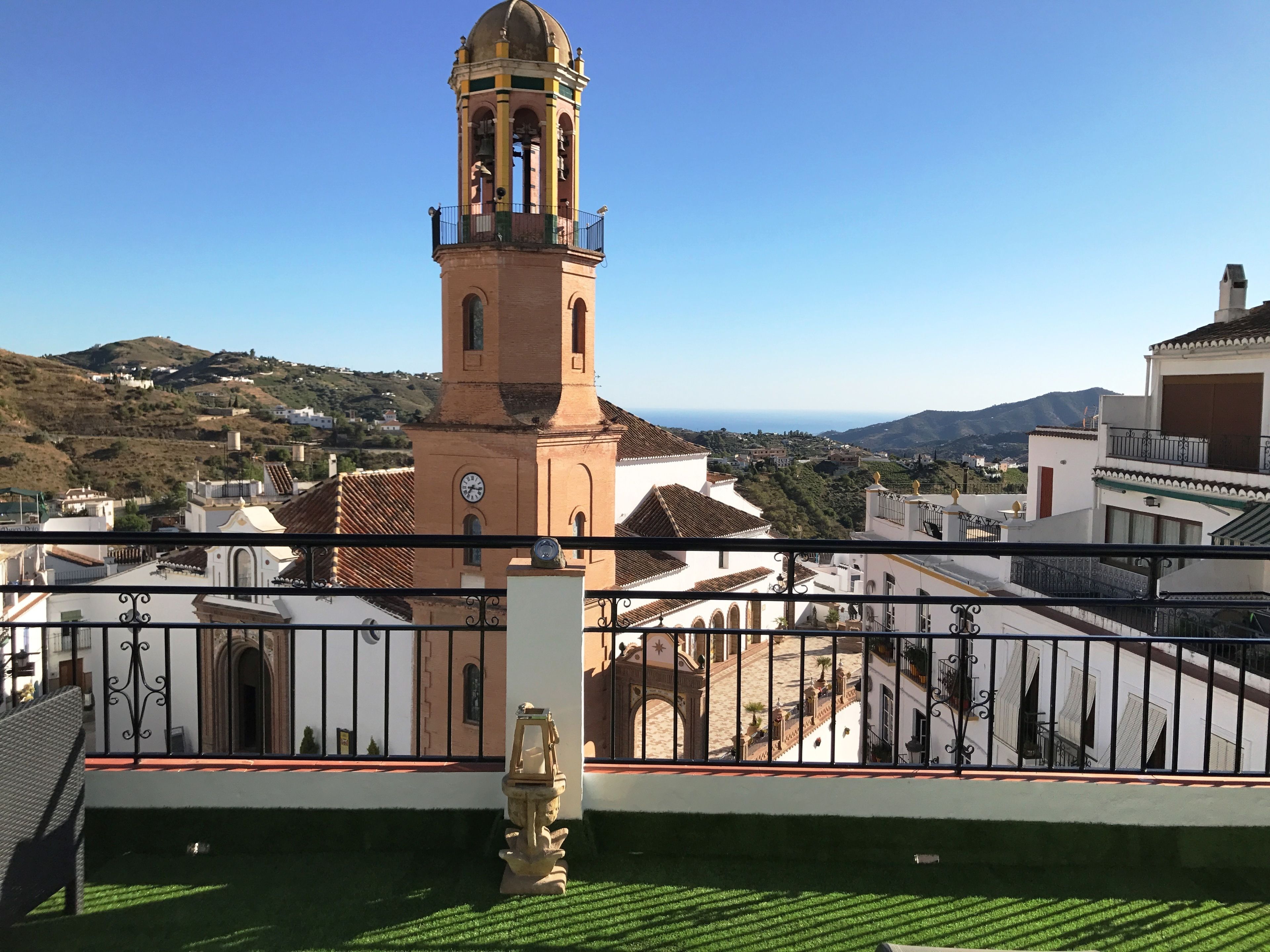 Una terraza con vistas a una torre histórica y edificios circundantes.