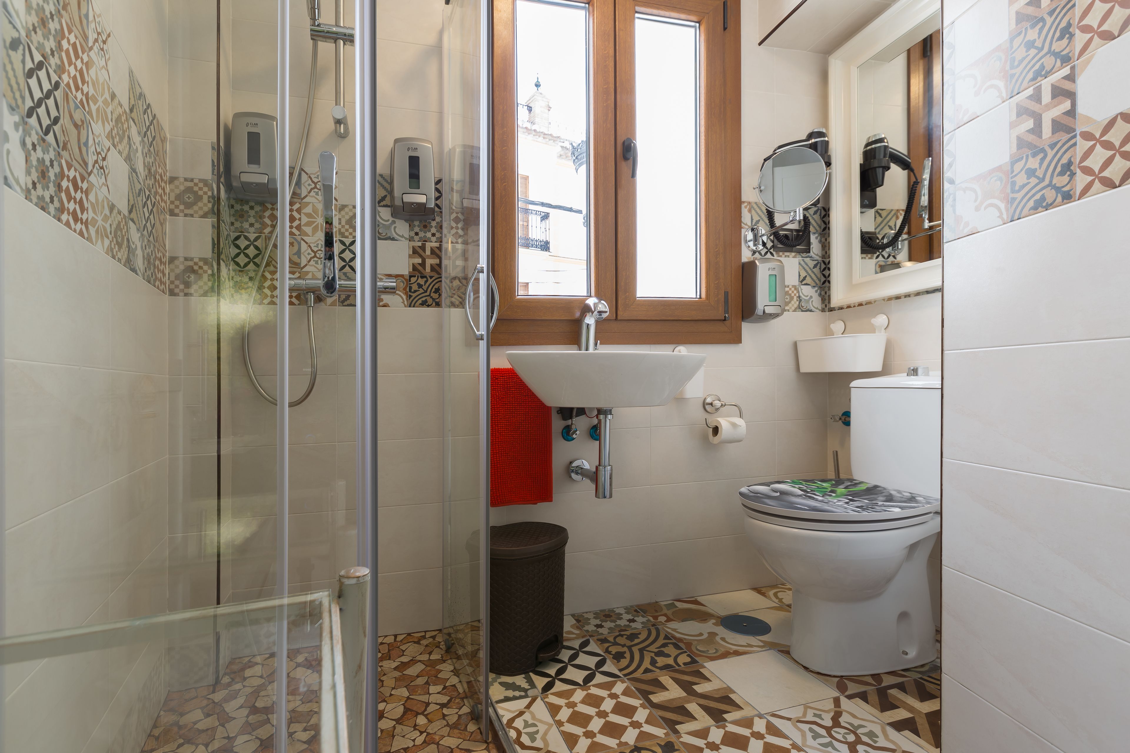 A bathroom with a shower, toilet, sink, and a window.