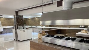 A modern kitchen with a stainless steel range hood, a granite countertop, and a wooden backsplash. - Corum Buyuk Otel (Corum)