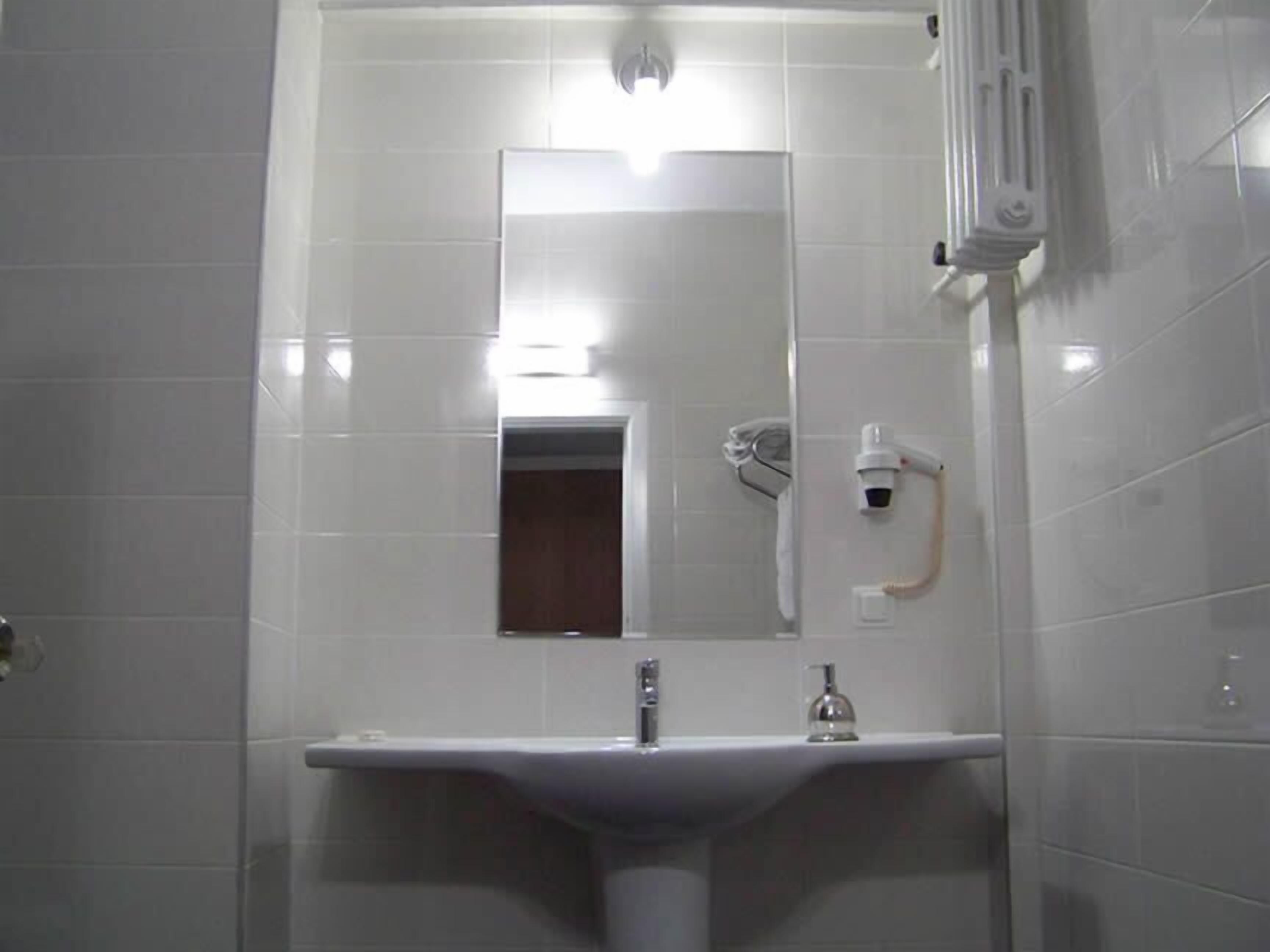 A bathroom with a white sink, a mirror, and a towel rack.