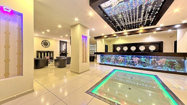 A hotel lobby with a reception desk, multiple clocks, a decorative ceiling, and a large aquarium. - Corum Buyuk Otel (Corum)