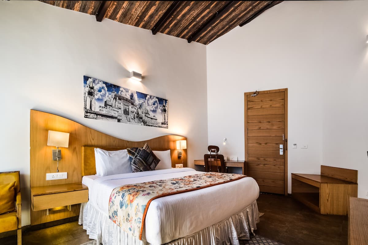 A neatly arranged bedroom with a bed, bedside tables, a desk, and a wooden door.