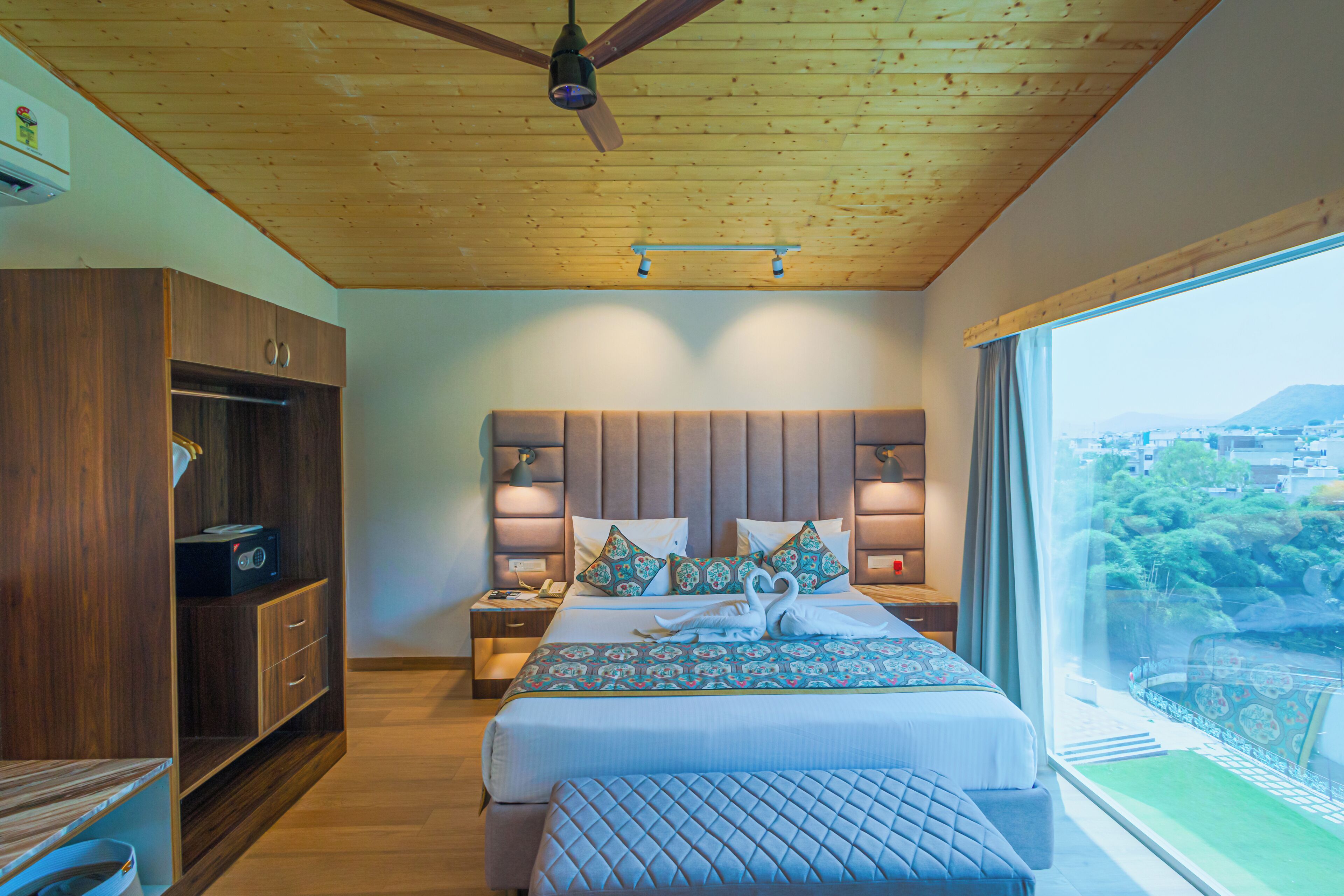 A bedroom with a wooden ceiling, a large bed with patterned bedding, a nightstand, and a wardrobe.