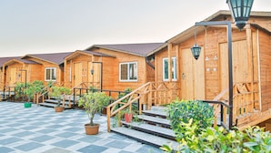 A row of wooden cabins with external stairs and potted plants. - Bamboo Saa Resort & Spa - Udaipur (Udaipur)