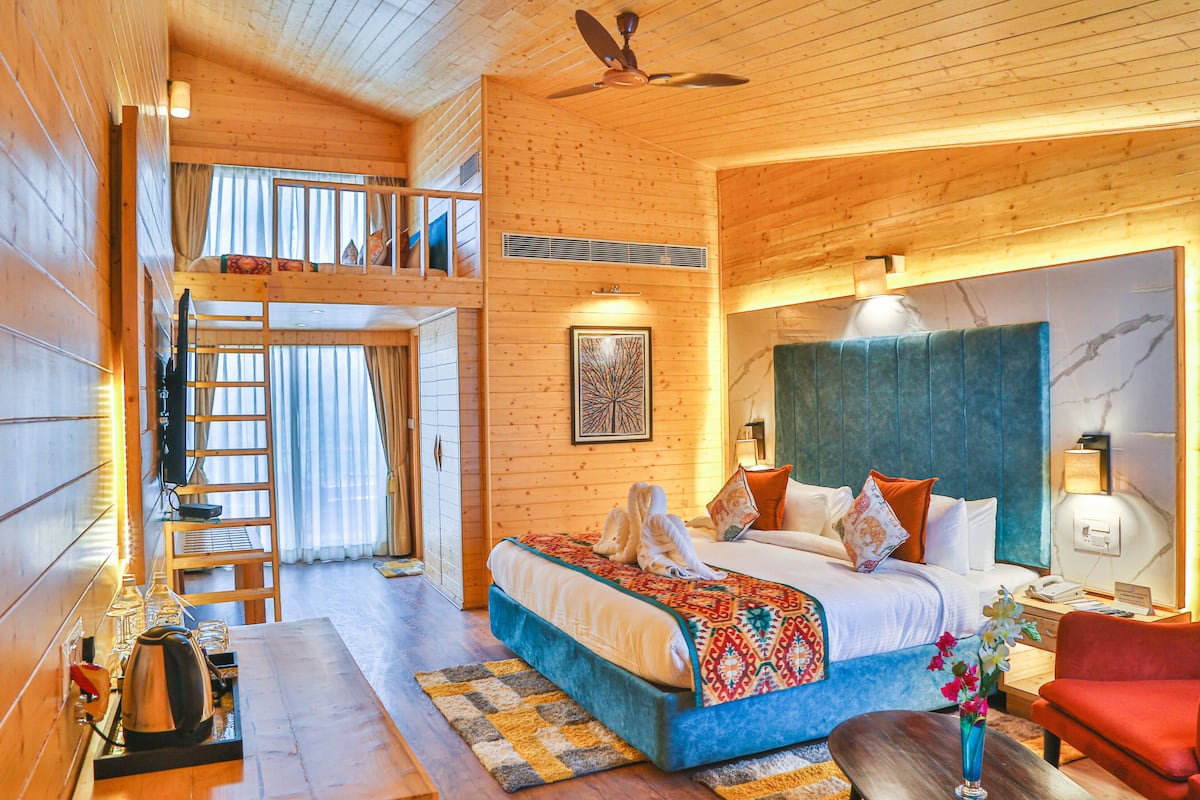 A wooden cabin bedroom with a bunk bed, a desk, and a red armchair.