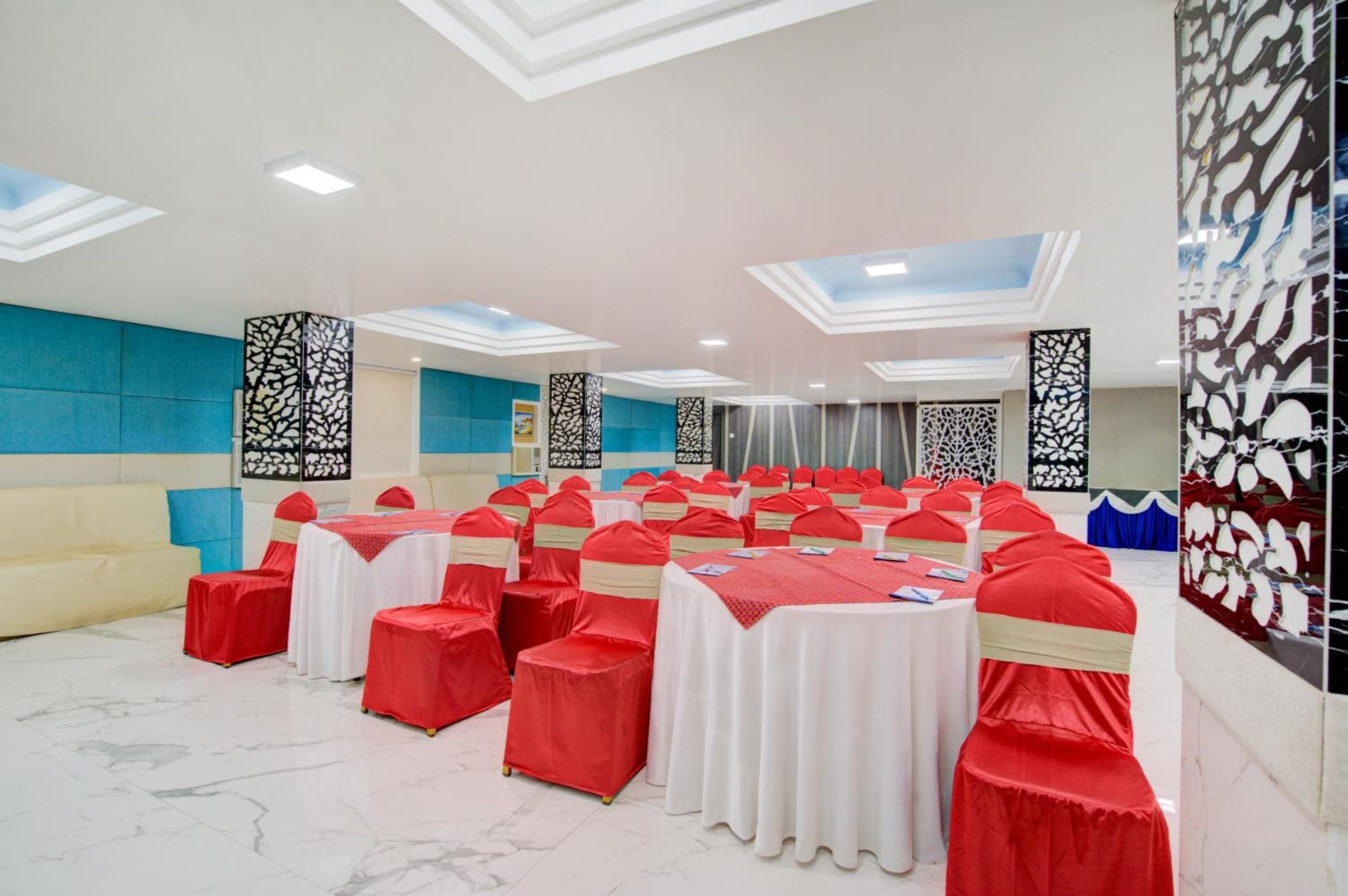A banquet hall with rows of tables and chairs, a high ceiling with skylights, and decorative panels.